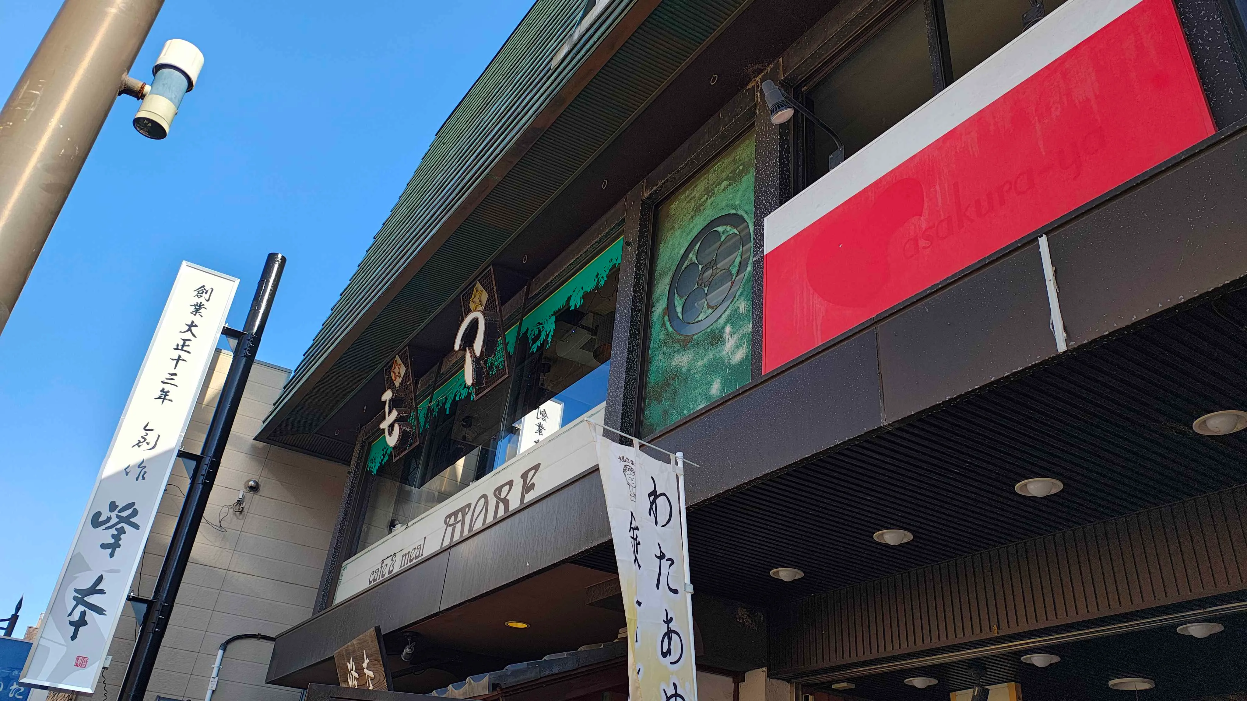 歩道から見上げた喫茶モアの外観。庇に MORE の看板が出ている
