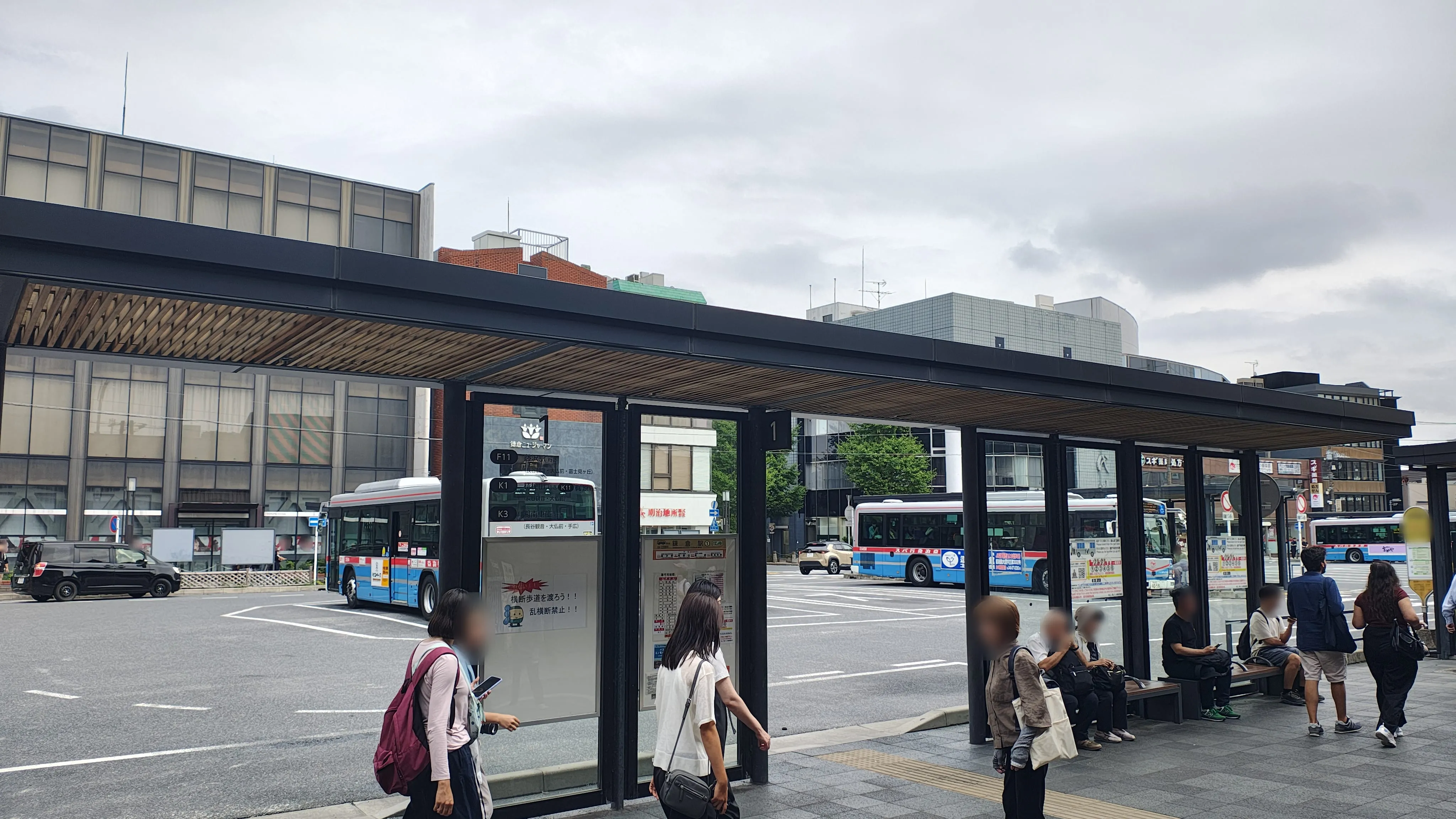 のりば1のシェルター。木のルーバーの屋根の下にベンチがあり、人が座って待っている